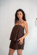 Woman wearing a brown dress against a white tiled wall - Cotton