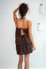 Woman wearing a brown dress with a white tiled wall background