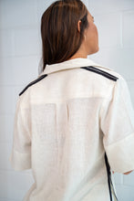 Person wearing a white Shirt with black accents on a plain background